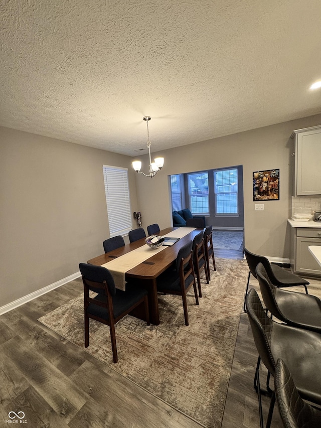 dining room with a notable chandelier, dark wood-type flooring, and a textured ceiling