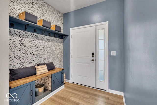 mudroom with light wood-style floors, an accent wall, and baseboards