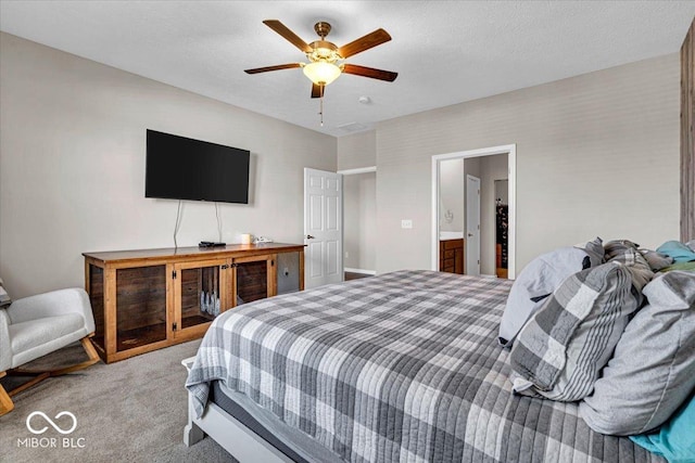 bedroom featuring light carpet, a textured ceiling, ensuite bath, and a ceiling fan