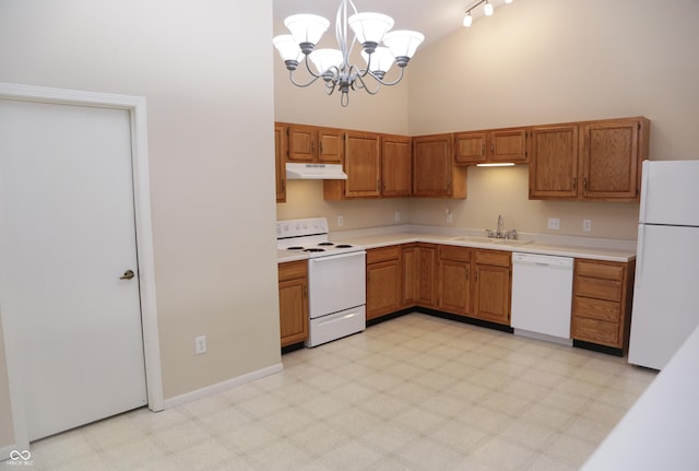 kitchen with a towering ceiling, sink, hanging light fixtures, a notable chandelier, and white appliances