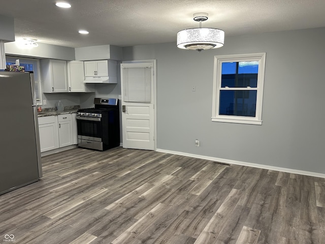 kitchen featuring stainless steel appliances, white cabinetry, a textured ceiling, and dark hardwood / wood-style flooring