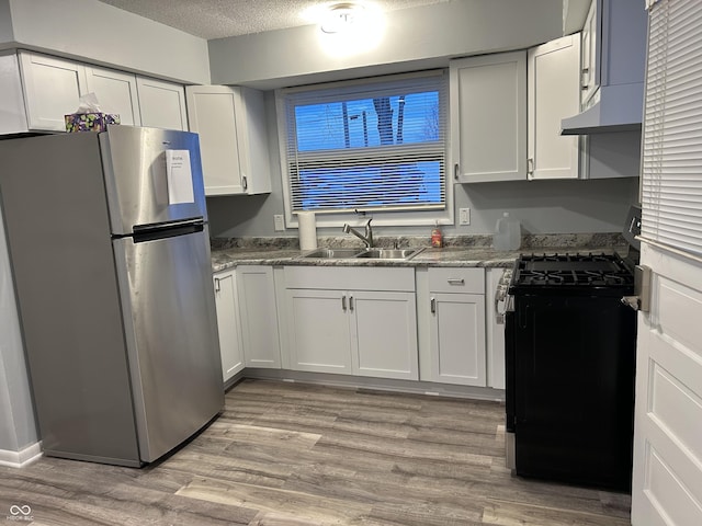 kitchen with sink, white cabinets, stainless steel refrigerator, and black range with gas cooktop