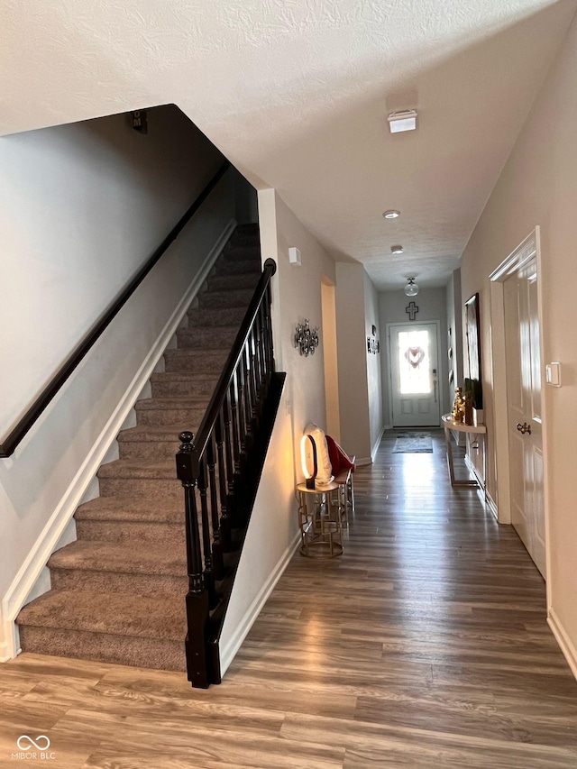 interior space featuring stairs, a textured ceiling, wood finished floors, and baseboards