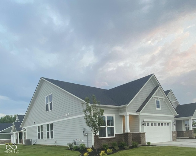 craftsman-style house with central air condition unit, a front lawn, concrete driveway, and brick siding