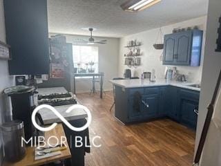 kitchen with blue cabinets, ceiling fan, kitchen peninsula, dark wood-type flooring, and a textured ceiling