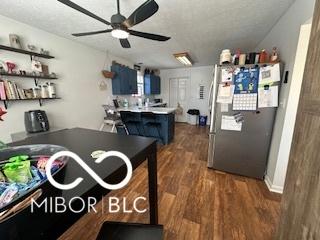 kitchen featuring dark wood-type flooring, blue cabinets, stainless steel refrigerator, kitchen peninsula, and ceiling fan