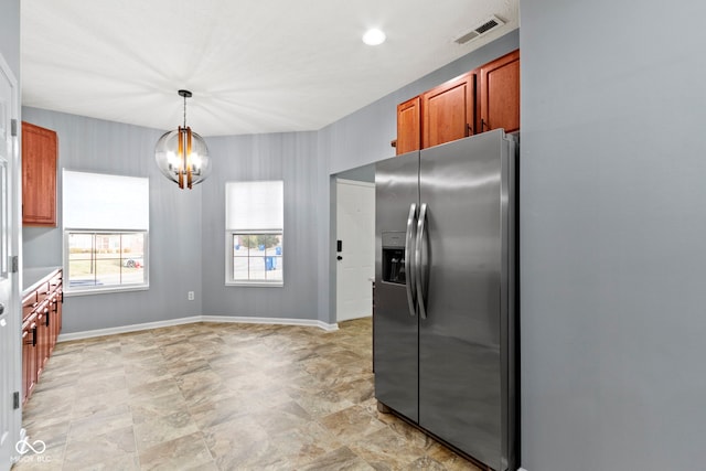 kitchen featuring stainless steel refrigerator with ice dispenser, hanging light fixtures, and a notable chandelier