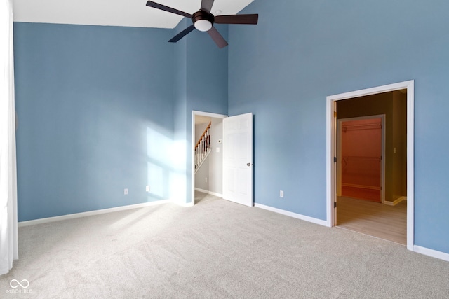 spare room featuring ceiling fan, light colored carpet, and a towering ceiling