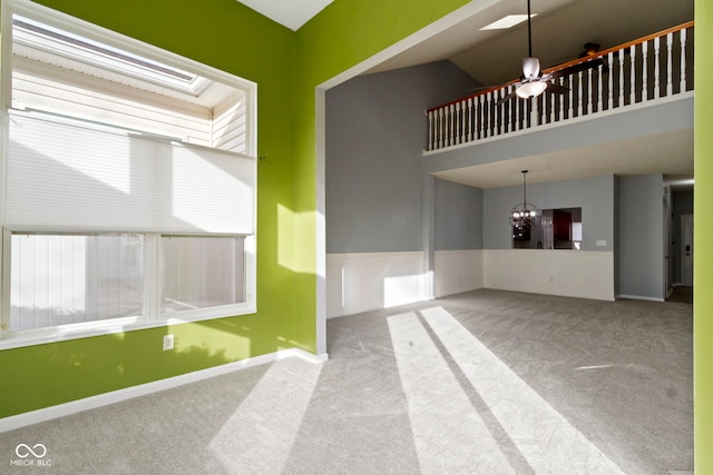 carpeted spare room with ceiling fan with notable chandelier