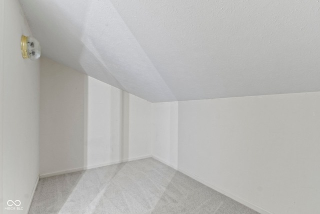 bonus room featuring lofted ceiling, light colored carpet, and a textured ceiling