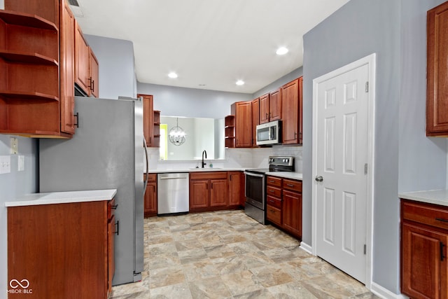 kitchen with pendant lighting, appliances with stainless steel finishes, sink, and backsplash