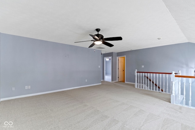 spare room featuring ceiling fan, vaulted ceiling, light colored carpet, and a textured ceiling