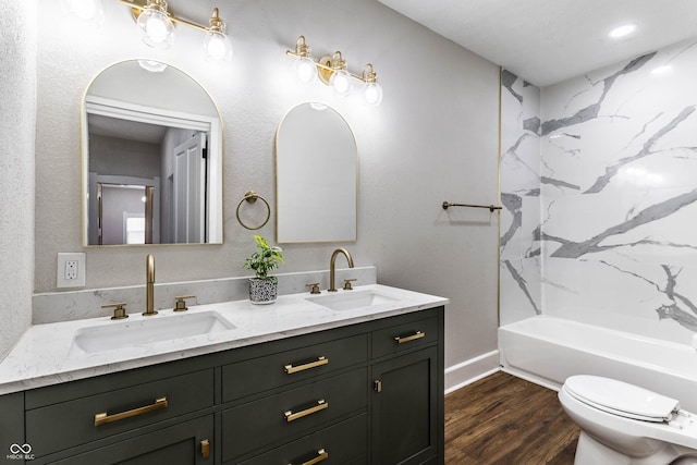 full bathroom with hardwood / wood-style flooring, tiled shower / bath, vanity, and toilet