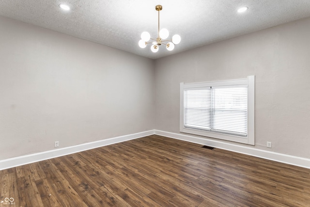 spare room with a chandelier, a textured ceiling, and dark hardwood / wood-style flooring