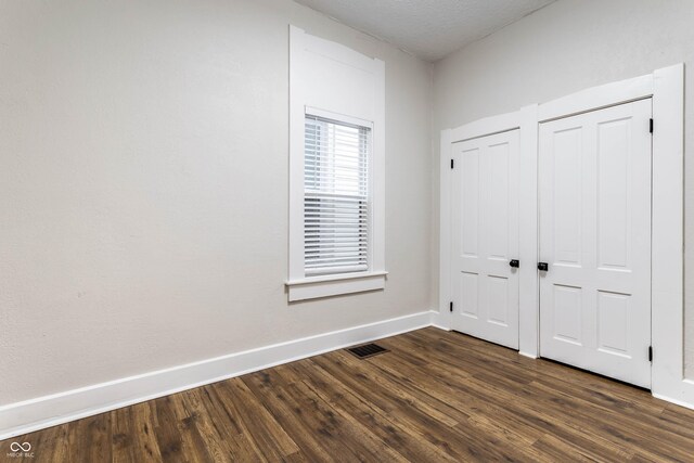 interior space with dark hardwood / wood-style floors, two closets, and a textured ceiling