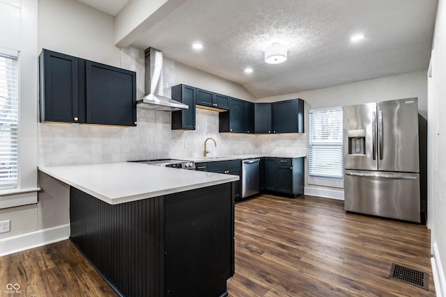 kitchen with stainless steel appliances, dark wood-type flooring, wall chimney range hood, and kitchen peninsula