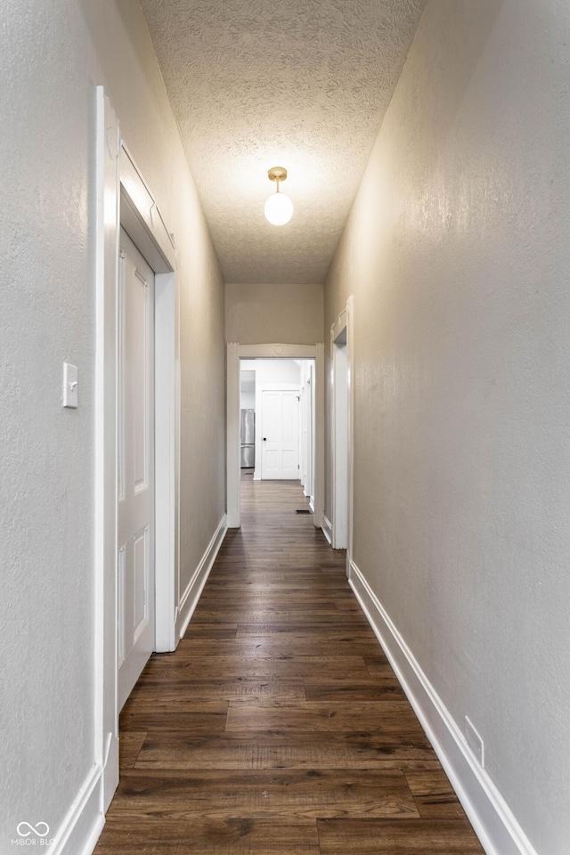 corridor with dark wood-type flooring and a textured ceiling