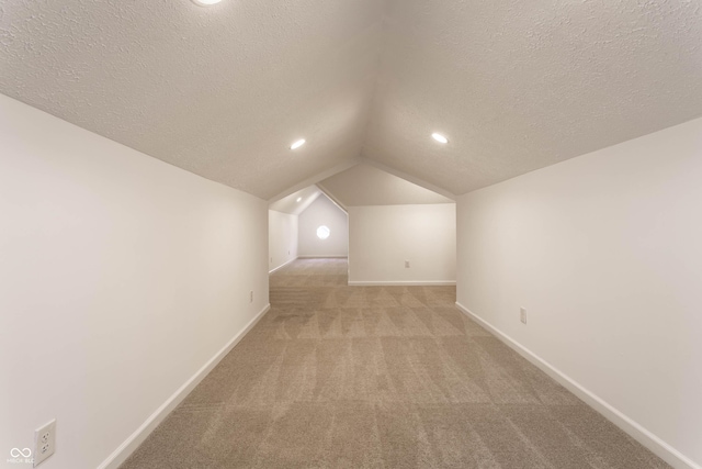 additional living space with lofted ceiling, light carpet, and a textured ceiling