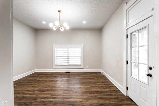 interior space with dark wood-type flooring, a wealth of natural light, a textured ceiling, and an inviting chandelier