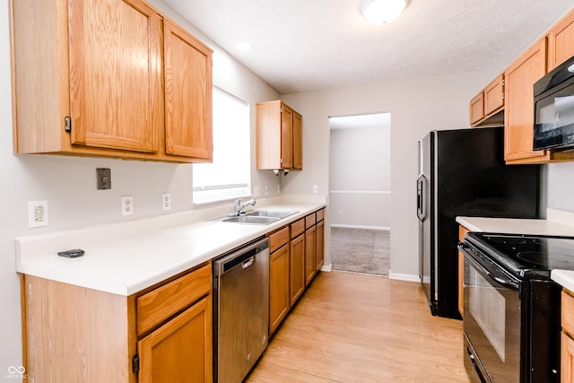 kitchen featuring a sink, light wood-style floors, baseboards, light countertops, and black appliances