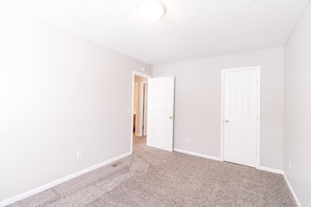 unfurnished bedroom featuring carpet, visible vents, baseboards, and a textured ceiling