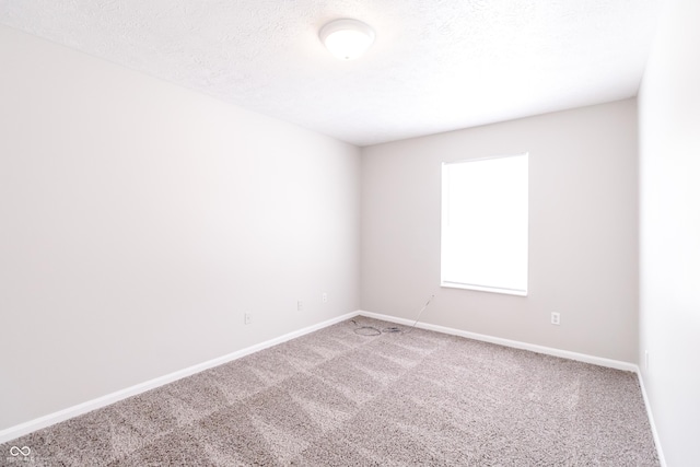 carpeted spare room featuring baseboards and a textured ceiling