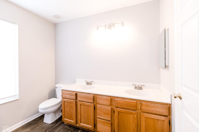 full bathroom featuring double vanity, toilet, a sink, and wood finished floors