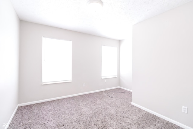 empty room featuring a textured ceiling, carpet floors, and baseboards