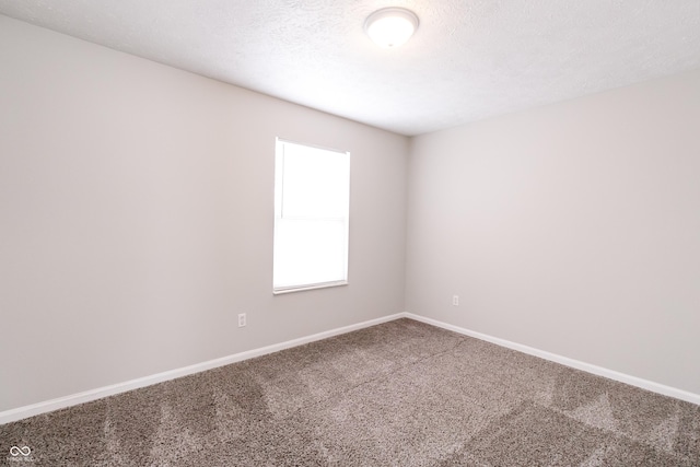 carpeted empty room with a textured ceiling and baseboards