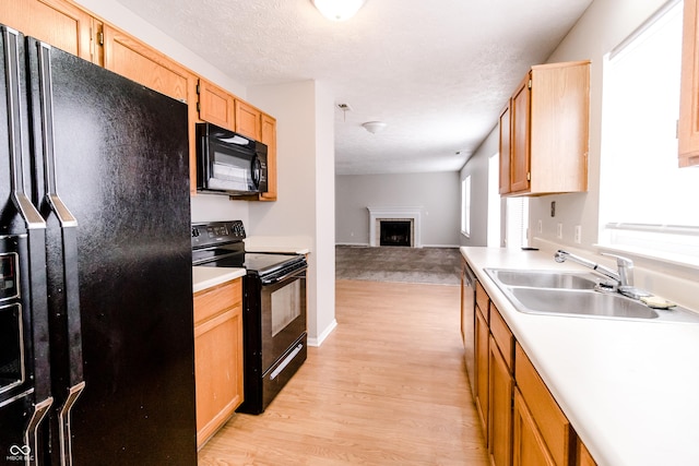 kitchen featuring black appliances, a fireplace, light countertops, and a sink