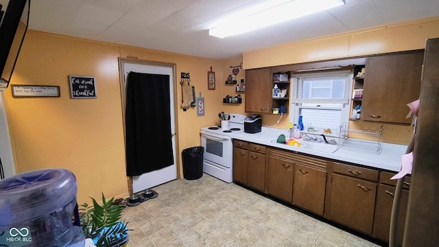 kitchen featuring white electric stove, dark brown cabinets, sink, and stainless steel refrigerator