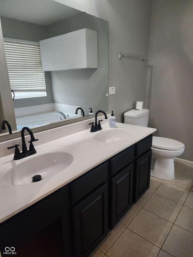 bathroom featuring vanity, a tub to relax in, tile patterned floors, and toilet