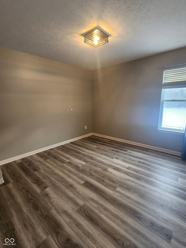 spare room with dark hardwood / wood-style floors and a textured ceiling