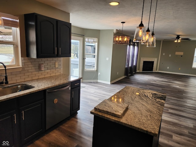 kitchen featuring sink, dishwasher, hanging light fixtures, a kitchen island, and decorative backsplash