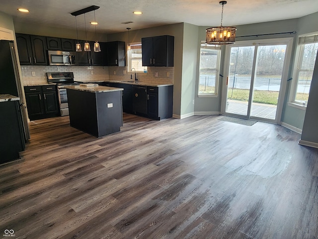 kitchen featuring pendant lighting, sink, stainless steel appliances, a center island, and decorative backsplash