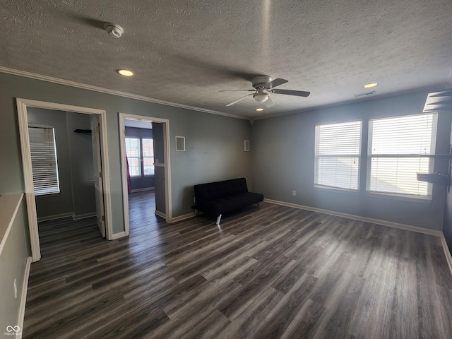 interior space featuring dark wood-type flooring, ceiling fan, ornamental molding, and a textured ceiling