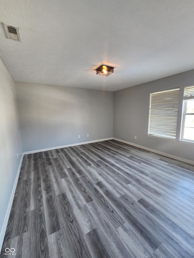 spare room featuring dark hardwood / wood-style floors and a textured ceiling