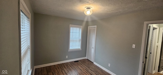 unfurnished bedroom featuring dark wood-type flooring, a closet, and a textured ceiling