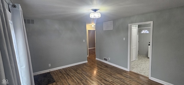 spare room featuring visible vents, baseboards, and wood finished floors