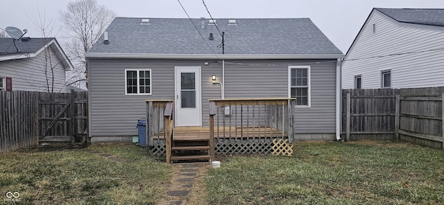 rear view of house featuring a lawn, a fenced backyard, and a shingled roof