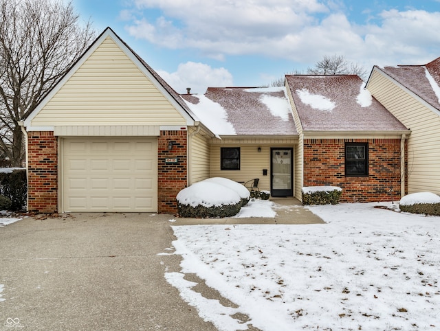 ranch-style home with a garage, driveway, brick siding, and a shingled roof