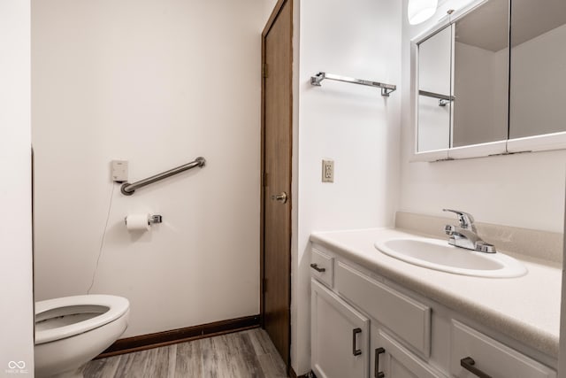 half bath featuring toilet, wood finished floors, vanity, and baseboards