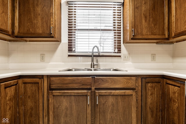 kitchen with light countertops, backsplash, and a sink