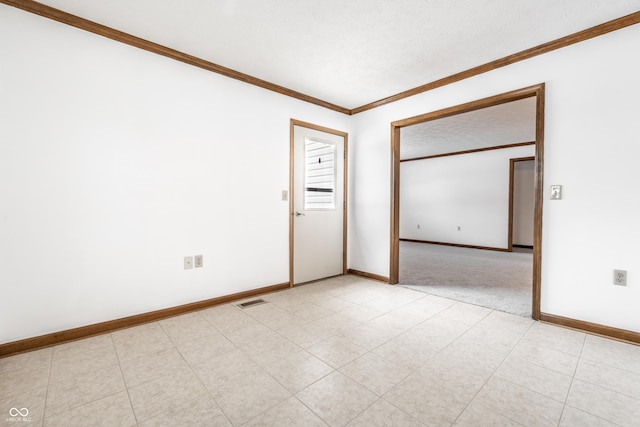 empty room with baseboards, a textured ceiling, visible vents, and crown molding