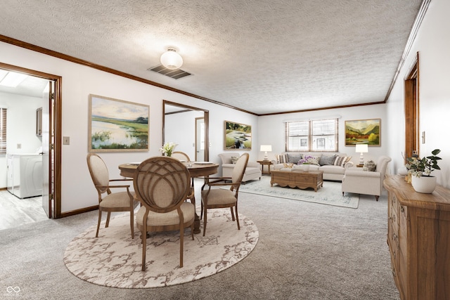 dining space featuring light colored carpet, visible vents, ornamental molding, a textured ceiling, and washer / dryer