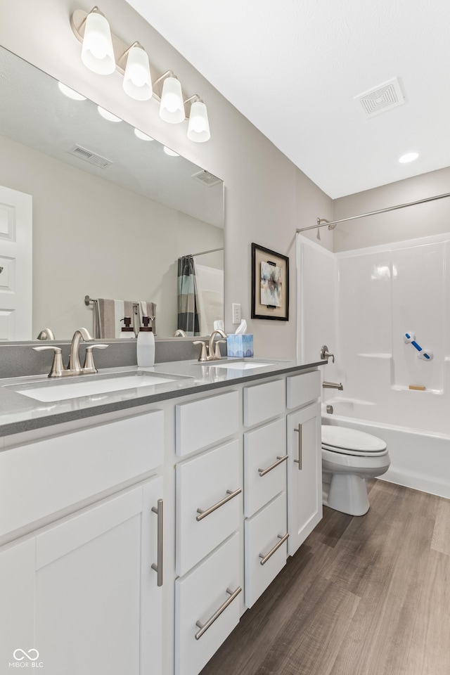 full bathroom with hardwood / wood-style flooring, shower / tub combo with curtain, vanity, and toilet