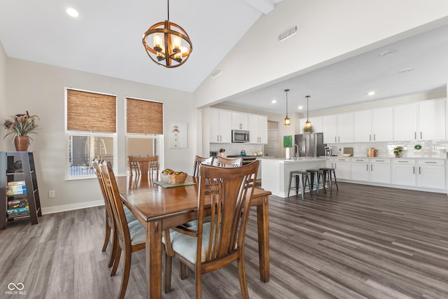 dining space featuring an inviting chandelier, sink, dark hardwood / wood-style floors, and high vaulted ceiling