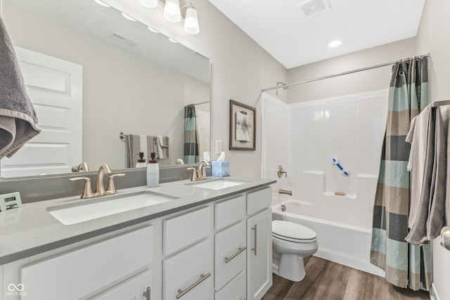 full bathroom featuring wood-type flooring, toilet, vanity, and shower / bath combo