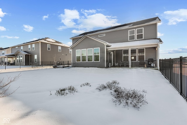 snow covered rear of property with a sunroom