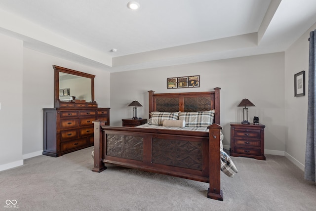 bedroom with a tray ceiling and light colored carpet